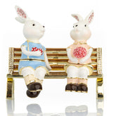 2 bunnies in love sitting on a bench, valentine flowers and chocolates